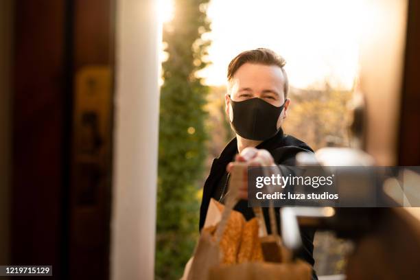 man with face mask delivering food - meal box stock pictures, royalty-free photos & images