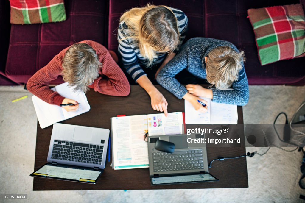 Mãe em casa estudando seus filhos