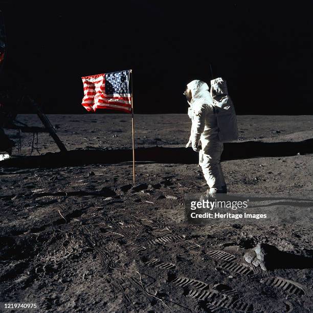 Apollo 11 Astronaut Edwin E. "Buzz" Aldrin, Jr., beside the U.S. Flag during an Apollo 11 moon walk. The Lunar Module is on the left, and the...