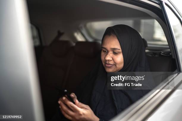 donna del medio oriente araba che usa il cellulare in auto - dubai taxi foto e immagini stock