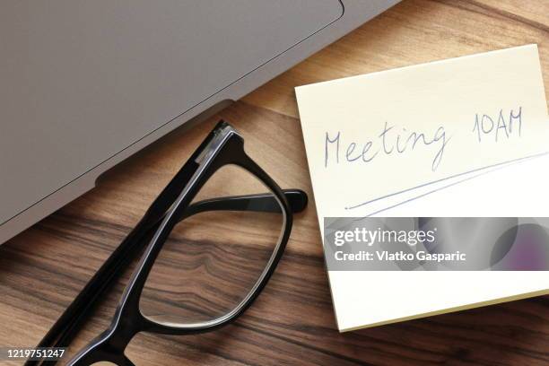 close-up of laptop and eyeglasses on wooden desk with adhesive sticky note - agenda meeting stock pictures, royalty-free photos & images