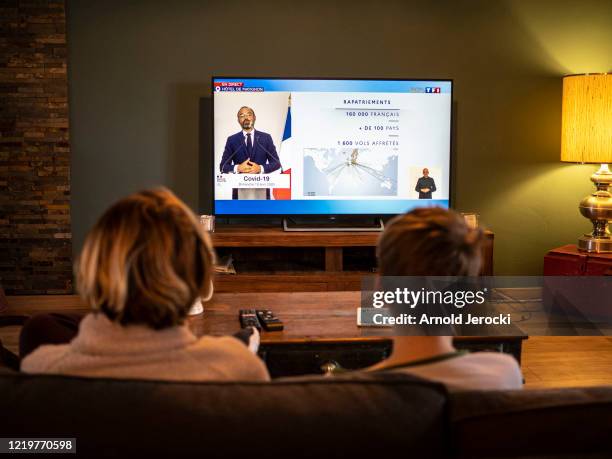 Photographer's family watche as French Prime Minister Edouard Philippe speaks from the Hotel de Matignon during a televised address to the nation on...