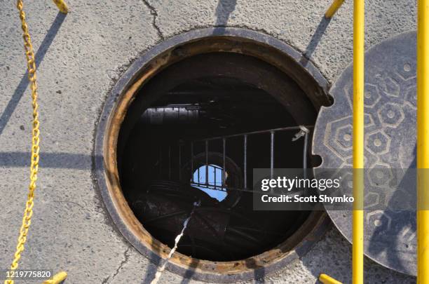 an open manhole on a city street - égout photos et images de collection