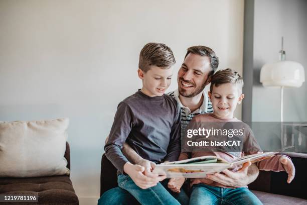 padre che legge un libro ai suoi figli - family with two children foto e immagini stock