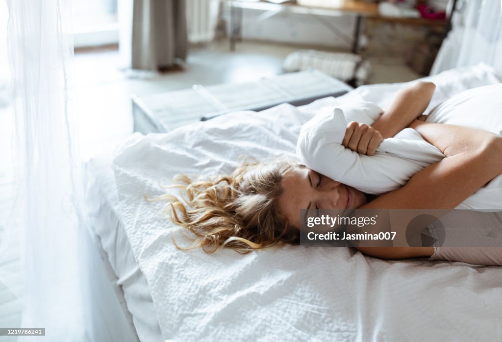 Porträt einer jungen Frau, die die Zeit im Bett genießt