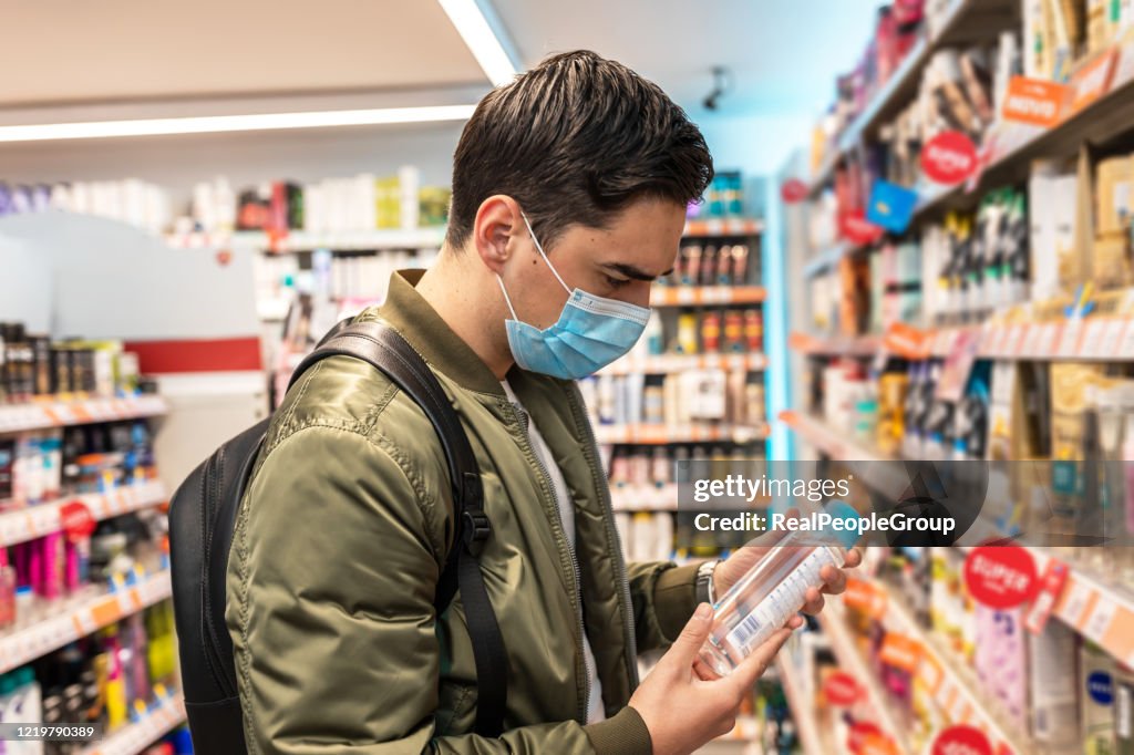 Homem com máscara facial andando e fazendo compras em supermercado