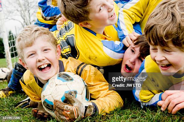 boys lying on grass with football - sportbegriff stock-fotos und bilder