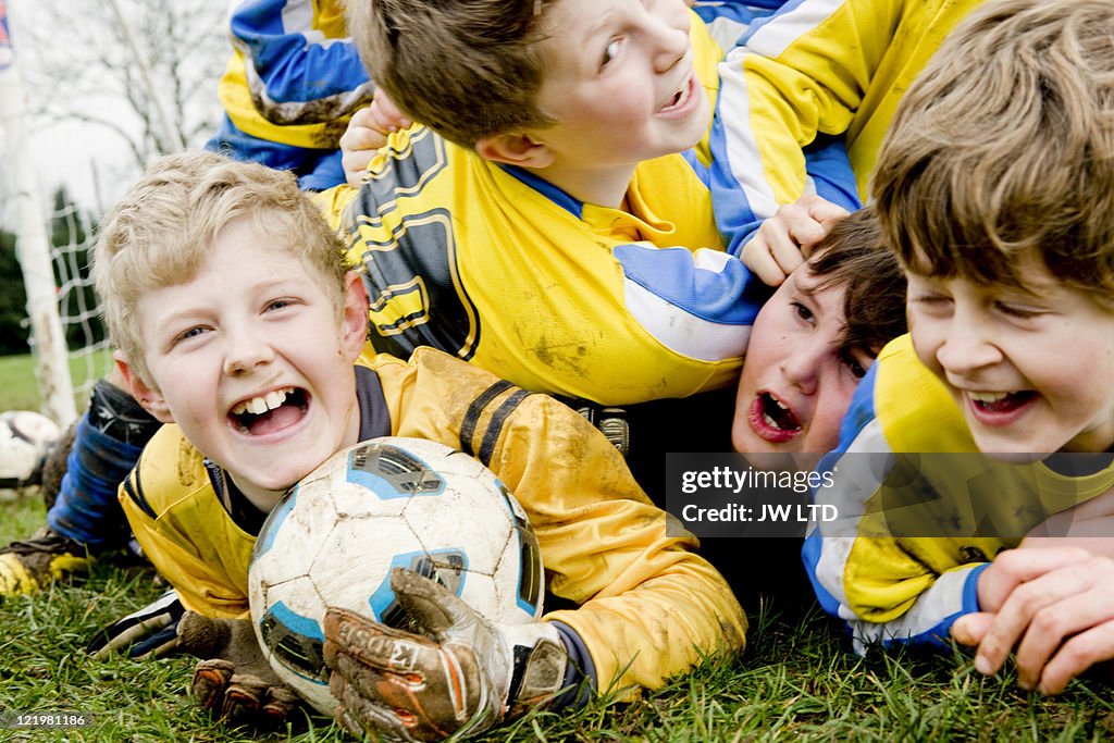 Boys lying on grass with football