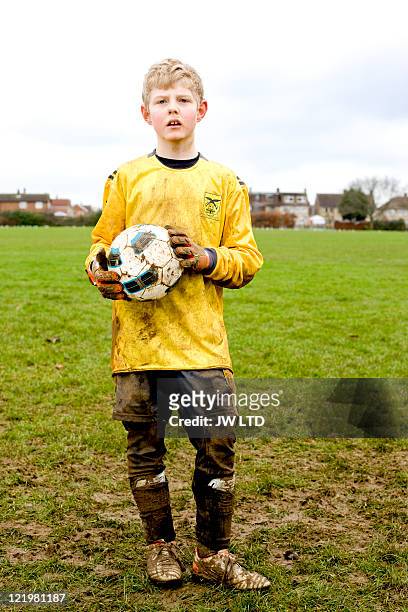 boy wearing football strip holding football, portrait - jungs stock-fotos und bilder