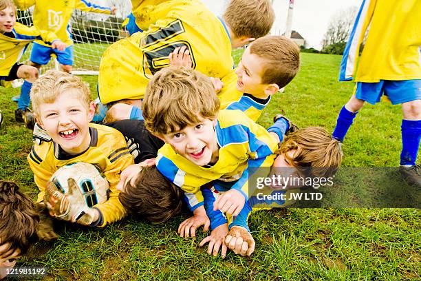 boys lying on grass with football - kids soccer stockfoto's en -beelden