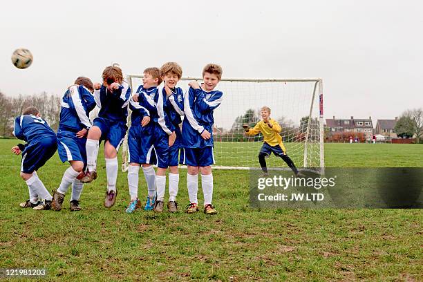 boys defending free kick during football game - football team stock pictures, royalty-free photos & images