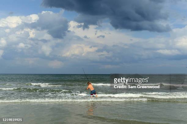 Person fishes in the surf on April 19, 2020 in Jacksonville Beach, Florida. Jacksonville Mayor Lenny Curry announced Thursday that Duval County's...