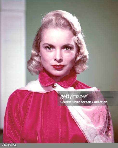Janet Leigh , US actress, wearing a high-neck red satin blouse, with a white floral print scarf fastened at the neck in a studio portrait, circa 1955.