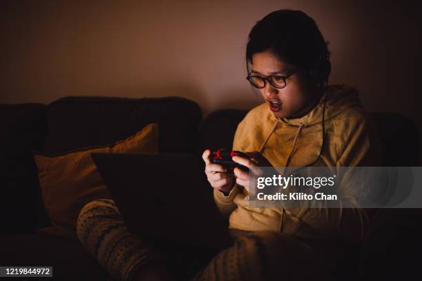 asian woman using laptop to play video games at home - gaming controller stock-fotos und bilder