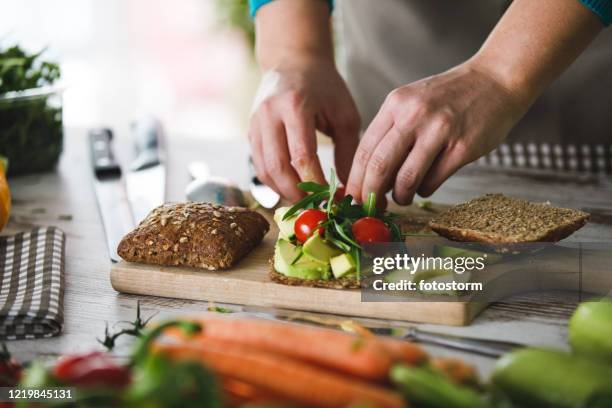 lägga till färska körsbärstomater till hälsosam vegansmörgås - sandwich bildbanksfoton och bilder