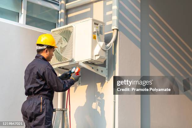 asian male technician repairing air conditioner safety uniform, technician vacuum pump evacuates and checking new air conditioner. - aire acondicionado fotografías e imágenes de stock