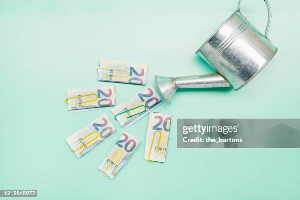 watering can and euro banknotes on turquoise background - fajo de billetes de euro fotografías e imágenes de stock