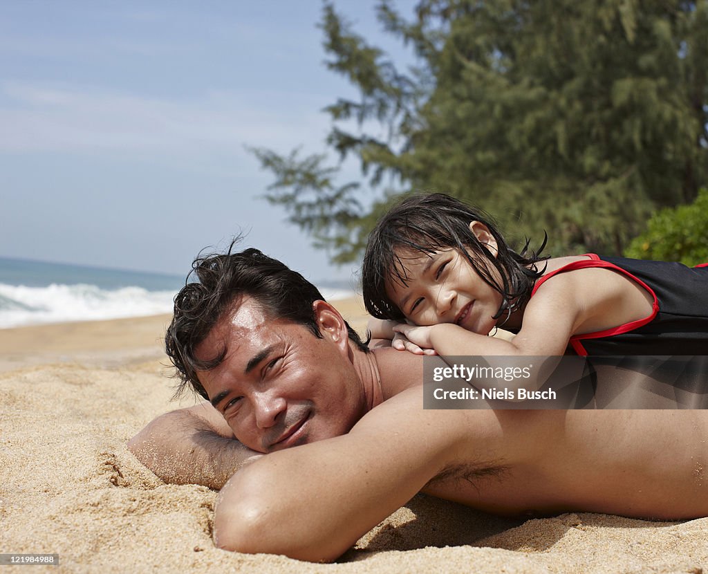 Father and daughter relaxing on beach
