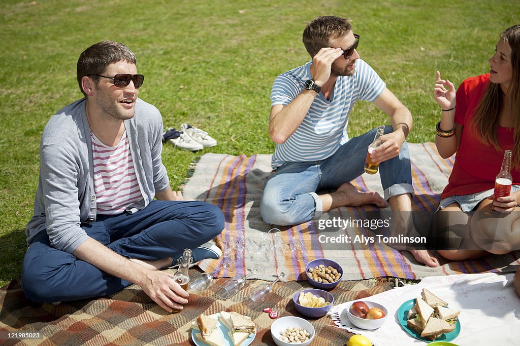 Three People Enjoying a Picnic in a City Park