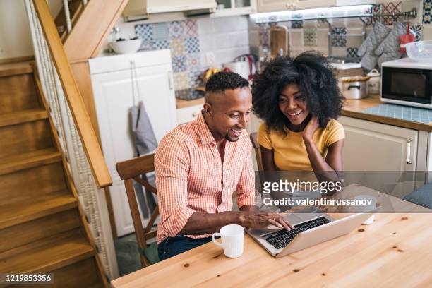 couple at home doing teleconferencing while stay at home during isolation - couple searching the internet stock pictures, royalty-free photos & images