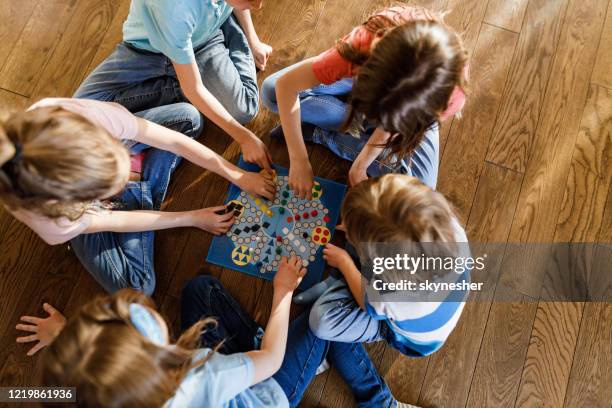 boven mening van groep jonge geitjes die ludospel op vloer spelen. - bordspel stockfoto's en -beelden