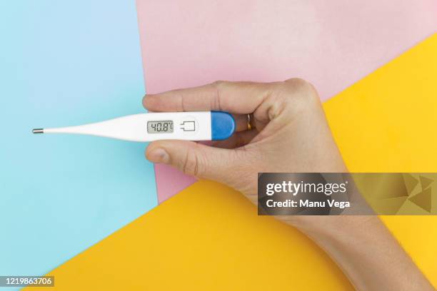 female doctor holding digital thermometer on background pastel pink, blue and yellow background, closeup. - stock photo - digital thermometer stock pictures, royalty-free photos & images