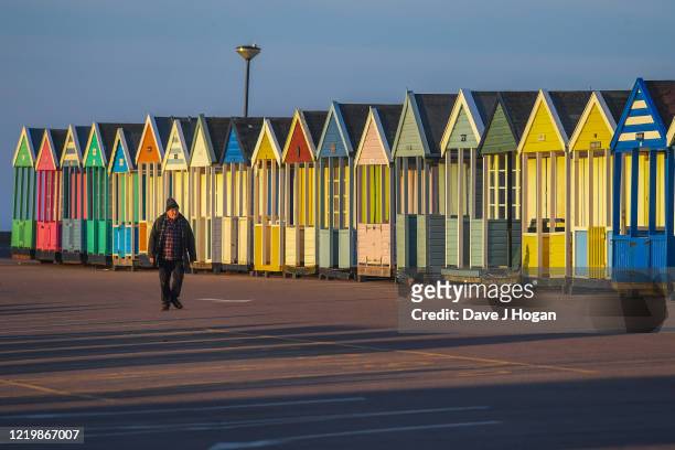 Man walks past beach huts in Southwold on April 15, 2020 in Southwold, United Kingdom. In a press conference on Thursday, First Secretary of State...