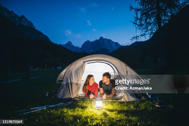 テントポーチに横たわるキャンプカップルと眺めの良い - ランタン ストックフォトと画像