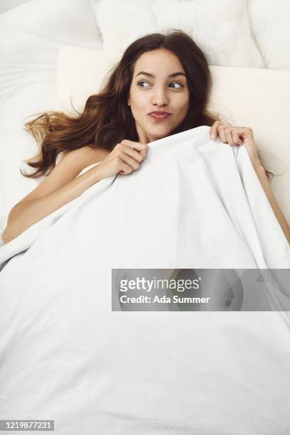 portrait of woman in bed , white linen - woman pillow over head stock-fotos und bilder