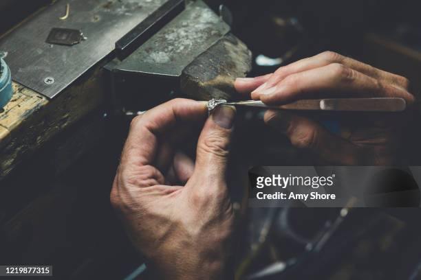 jeweller's hands working on diamond ring - juwelier stock-fotos und bilder