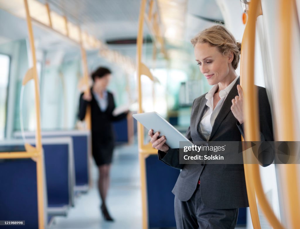 Businesswoman in train, holding tablet computer