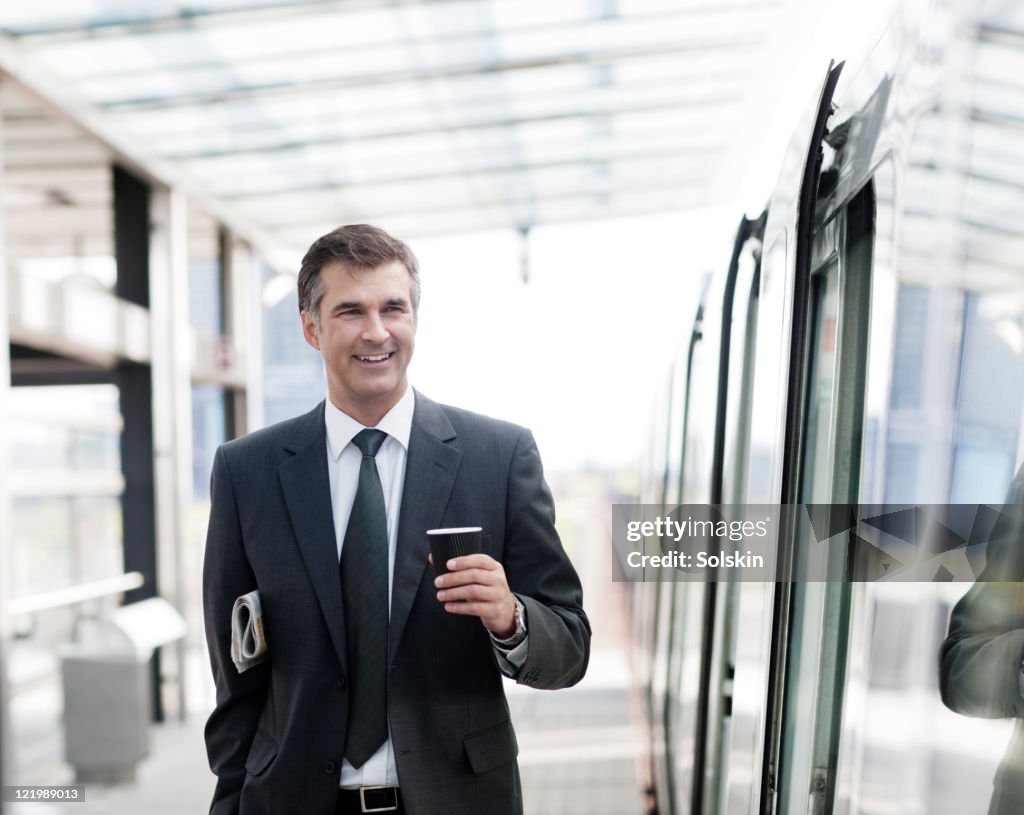 Businessman on train station, holding coffee