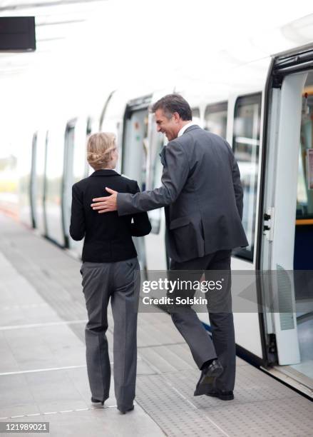 businessman and woman on trainstation - arm umlegen stock-fotos und bilder