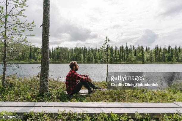 de zitting van de mens in het bos dichtbij de rivier - finnish nature stockfoto's en -beelden