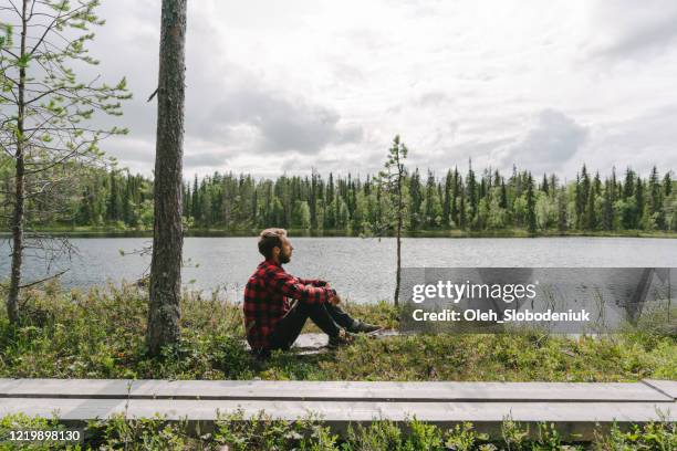 人坐在河邊的森林裡 - finland 個照片及圖片檔