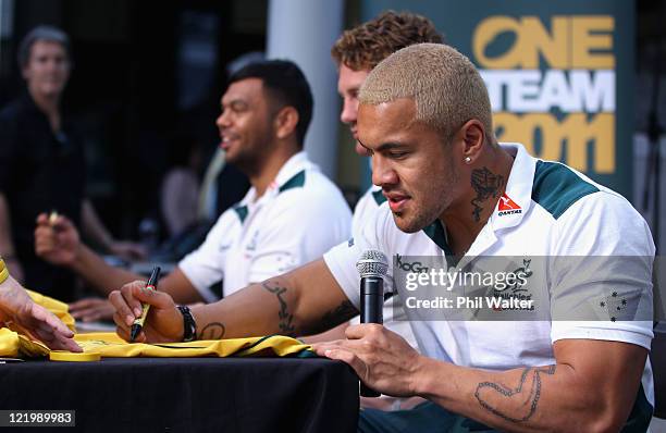 Digby Ioane of the Wallabies signs a jersey alongside Scott Higginbotham and Kurtley Beale during an Australian Wallabies signing session at Queen...