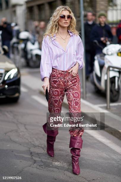 Romee Strijd wears a mauve pale purple shirt, a golden necklace, red pants with floral print, purple leather pointy boots, outside Etro, during Milan...