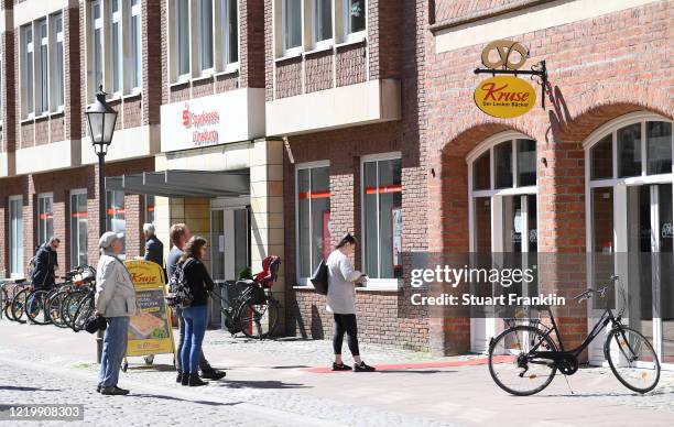 People practice social distancing as they wait outside a backery on the first day of the easing of some restrictions during the coronavirus crisis on...