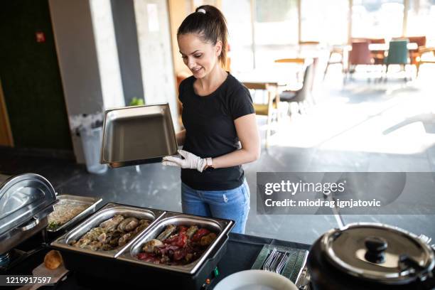 caterer, der bei der zubereitung des buffets gerichte mit herzhaften speisen zubereitet - catering buffet stock-fotos und bilder