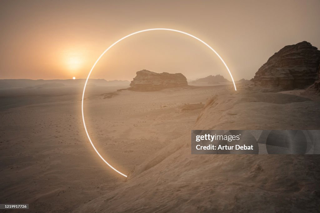 Futuristic circle made with neon lights in the desert landscape.