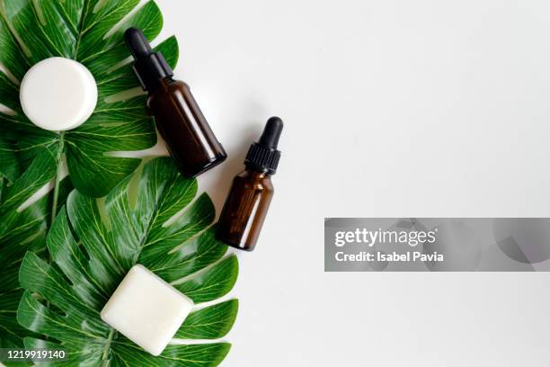 natural essential oils and green leaves on white background - hair spa foto e immagini stock