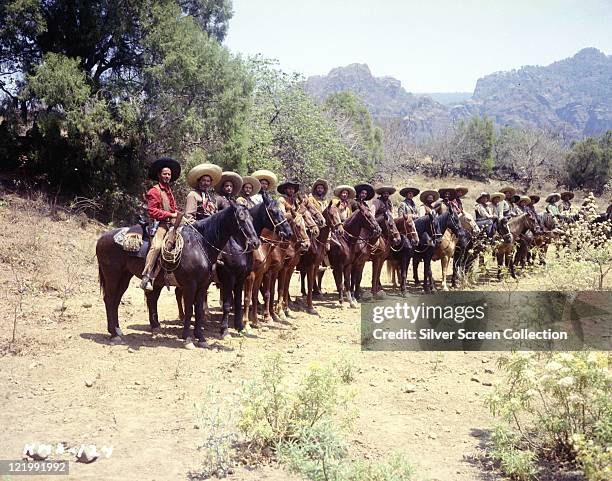 Eli Wallach, US actor, on horseback in the foreground at the head of a long line of Mexican bandits on horseback in a publicity still issued for the...