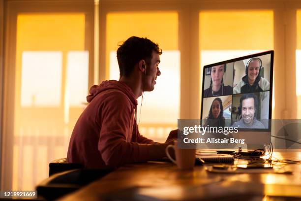 young man chatting to friends on video call from his home during lockdown - abstand halten infektionsvermeidung stock-fotos und bilder