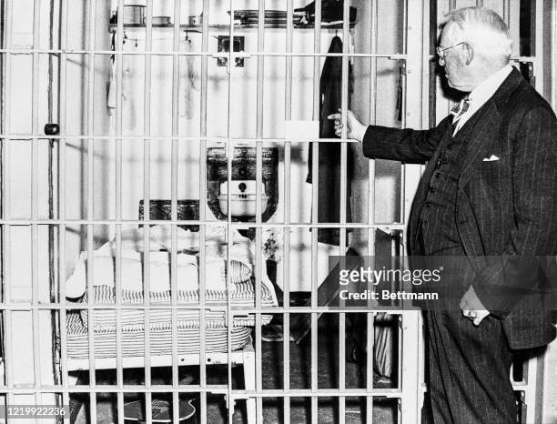 Photo shows the Warden of Alcatraz Federal Penitentiary, James A. Johnston , pointing into the cell in which seven prison guards were imprisoned by...
