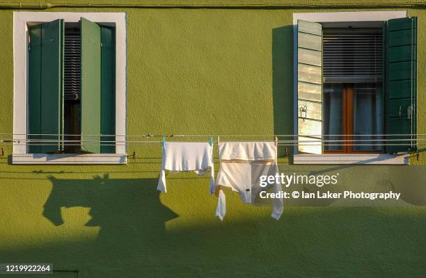 venice, italy. 5 march 2005. detail of colourful house with windows and clothes drying on line on the venetian island of burano. - venice italy stock-fotos und bilder