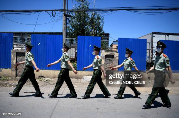 Chinese paramilitary policemen wearing face masks walk past the closed Xinfadi Market in Beijing on June 14, 2020. - The domestic COVID-19...