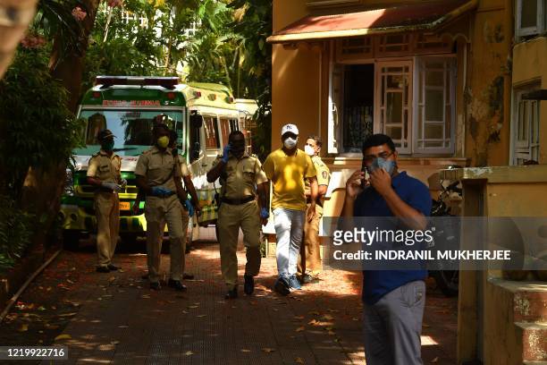 Police personnel stand near the ambulance carrying the body of Indian Bollywood actor Sushant Singh Rajput after he took his own life, at his...