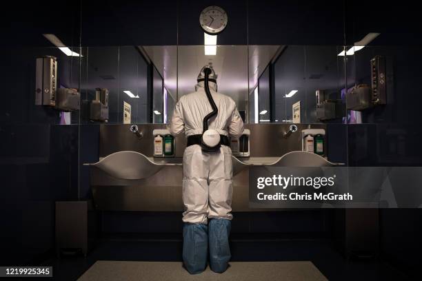 Dr. Mahmut Ozan Findik checks his personal protective equipment in a mirror ahead of performing a tracheotomy operation on a patient infected with...