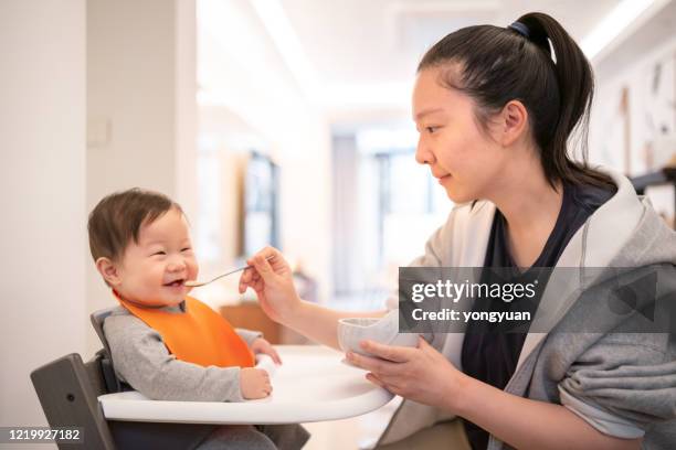 young asian mother feeding her baby son - asian spoon feeding stock pictures, royalty-free photos & images