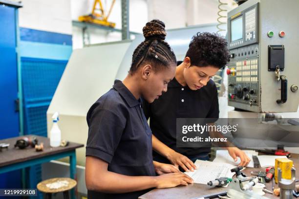 arbeiterinnen, die sich mit dem design von maschinenteilen in der fabrik befassen - drawing art product stock-fotos und bilder